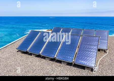 Reihen von Solarkollektoren auf dem Dach auf dem Meer Stockfoto