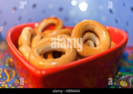 Close-up verglaste Bagels auf rotem Teller in Form von Herzen auf farbigem Hintergrund. Selektiven Fokus. Stockfoto