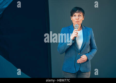 Elegante weibliche Fernsehjournalist tun Geschäft Reportage, Mikrofon in Händen hält, breaking News Konzept Stockfoto
