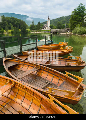 Wocheiner See (Bohinjsko Jezero), Triglav Nationalpark, obere Krain, Slowenien. Ruderboote zu mieten. Die Kirche des Hl. Johannes (Cerkev Sv Janeza) bei R Stockfoto