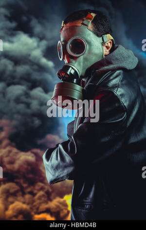 Bewaffneter Mann mit Gasmaske über Explosion Hintergrund Stockfoto