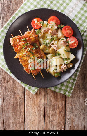 Spanische Pork Kabobs - Pinchos Morunos und einfach Kartoffeln mit Dressing - Patatas Alinadas Nahaufnahme auf einer Platte. vertikale Ansicht von oben Stockfoto