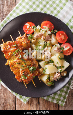 Spanische Küche: Kebab Pinchos Morunos und Gemüse Salat Nahaufnahme auf einem Teller auf den Tisch. vertikale Ansicht von oben Stockfoto