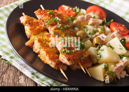 Spanische Küche: Kebab Pinchos Morunos und Gemüse Salat Nahaufnahme auf einem Teller auf den Tisch. Horizontale Stockfoto