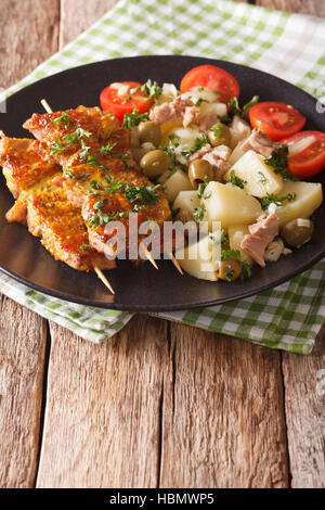 Spanische Küche: Kebab Pinchos Morunos und Gemüse Salat Nahaufnahme auf einem Teller auf den Tisch. vertikale Stockfoto