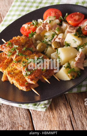 Spanische Kebab Pinchos Morunos und Salat Patatas Alinadas Nahaufnahme auf einer Platte. vertikale Stockfoto