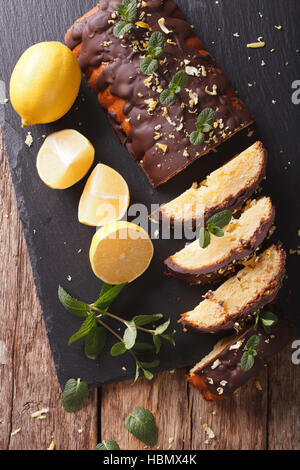 In Scheiben geschnitten Zitronenkuchen mit Schokoladenglasur und Lebensfreude hautnah auf dem Tisch. vertikale Ansicht von oben Stockfoto