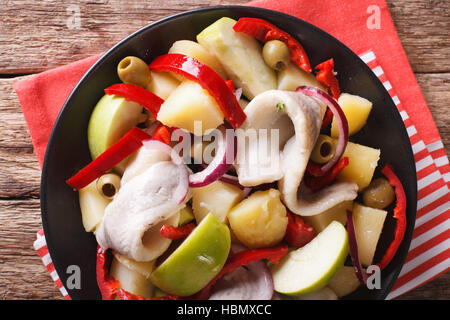 Heringssalat mit Kartoffeln, grünem Apfel, rote Zwiebel, Paprika und Oliven-close-up auf einem Teller auf den Tisch. horizontale Ansicht von oben Stockfoto