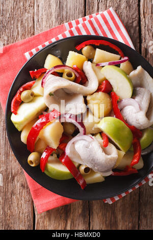 Heringssalat mit Kartoffeln, grünem Apfel, rote Zwiebel, Paprika und Oliven-close-up auf einem Teller auf den Tisch. vertikale Ansicht von oben Stockfoto