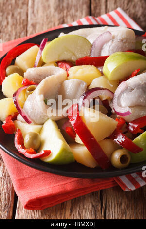 Heringssalat mit Kartoffeln, grünem Apfel, Zwiebel, Paprika und Oliven Nahaufnahme auf einem Teller auf den Tisch. vertikale Stockfoto