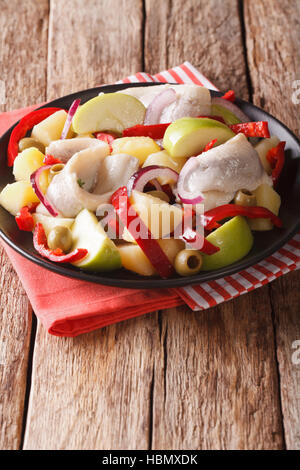 Heringssalat mit Kartoffeln, grünem Apfel, rote Zwiebel, Paprika und Oliven-close-up auf einem Teller auf den Tisch. vertikale Stockfoto