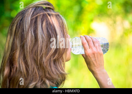 blonde Dame in Flaschen abgefülltes Trinkwasser außerhalb Stockfoto