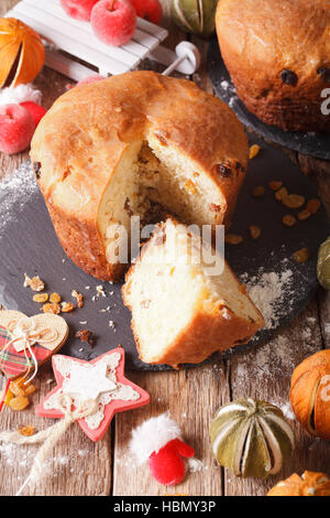 Hausgemachte Panettone-Brot mit Trockenfrüchten und Weihnachten Dekoration Nahaufnahme auf dem Tisch. vertikale Stockfoto