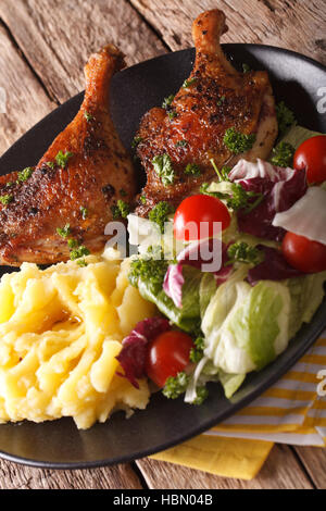 Gebratene Entenkeule mit Kartoffelpüree und frischem Salat auf der Platte Nahaufnahme. vertikale Stockfoto