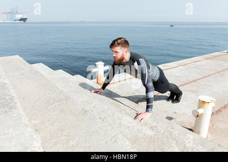Männliche tun Push Ups in der Nähe des Meeres. auf Treppen. Ansicht von oben Stockfoto
