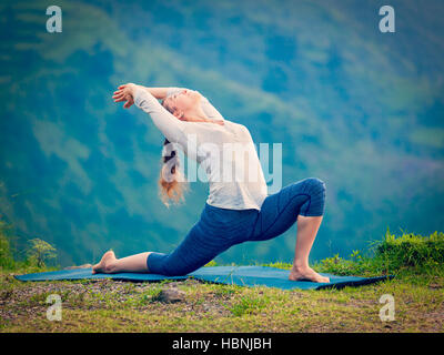 Sportlich Fit Frau Praktiken Yoga Asana Anjaneyasana in Bergen Stockfoto