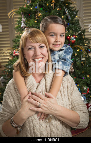 Glückliche Mutter und gemischten Rennen Sohn Hug in der Nähe von ihren Weihnachtsbaum. Stockfoto