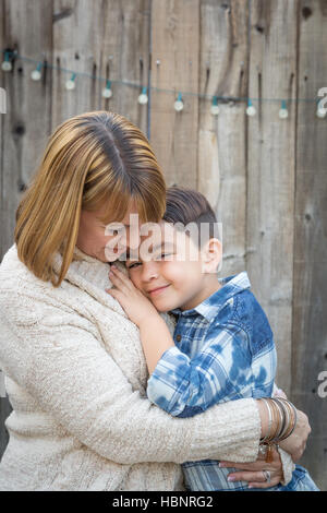 Liebevolle Mutter und gemischten Rennen Sohn Hug in der Nähe von Zaun. Stockfoto