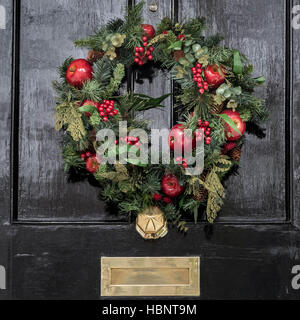 Eine festliche Weihnachten Kranz hängt an der Tür eines Hauses im Royal Borough von Kensington und Chelsea. London, Großbritannien. Stockfoto