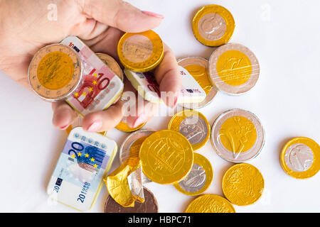 Hand der Frau, die Gold und Silberfolie umhüllte Schokoladengelder hält Stockfoto