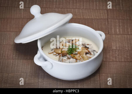 Teil des Pilzes pürieren Suppe in Keramiktopf auf Holztisch Stockfoto