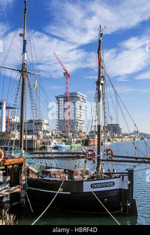 Zweimaster Segelschiff Nele und neue Wohnungen zu bauen für Immobilien-Projekt Oosteroever im Hafen von Ostende an der belgischen Nordseeküste Stockfoto