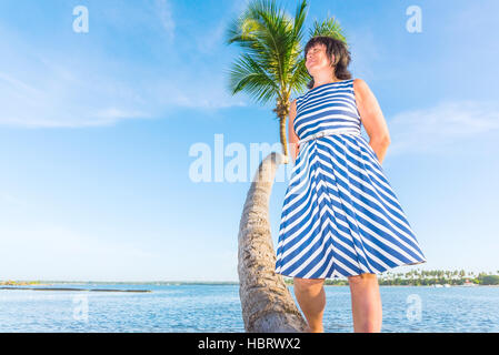 Brünette Frau mittleren Alters auf einer Palme Stockfoto