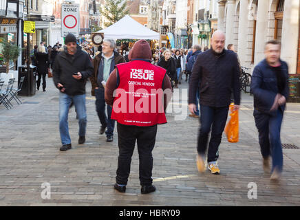 Menschen zu Fuß vorbei an Big Issue Magazin verkaeufers, Winchester, Hampshire, UK Stockfoto