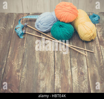 Garn Sie mit Stricknadeln auf hölzernen Hintergrund Stockfoto