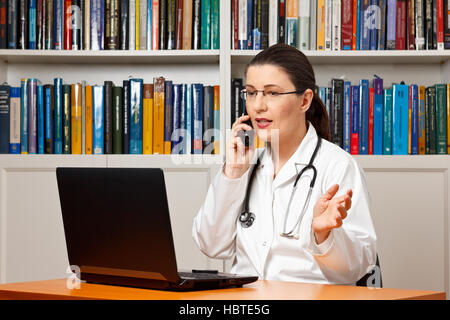 Frau Doktor an ihrem Schreibtisch sitzen vor einem Computer und ein Gespräch mit einem Patienten, Gesundheit Hotline, Beratung Stockfoto