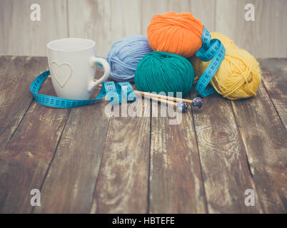 Garn Sie mit Stricknadeln auf hölzernen Hintergrund Stockfoto