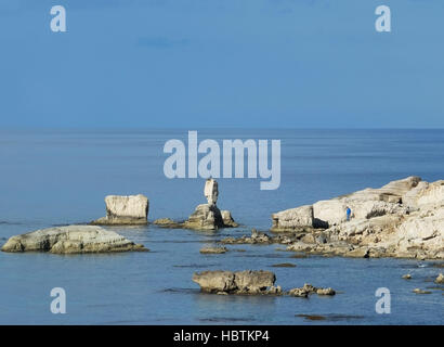 Ein Mann steht auf den Felsen am Meer Höhlen in der Nähe von Peyia im Bezirk Paphos. Stockfoto