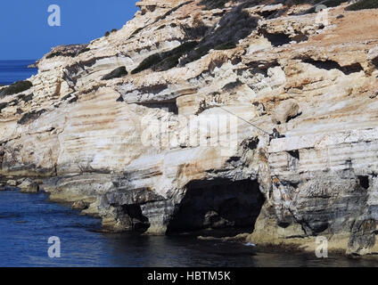 Ein Mann Fische aus den Felsen am Meer Höhlen in der Nähe von Peyia im Bezirk Paphos. Stockfoto