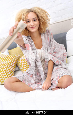 Frisur. Das Morgen-Styling. Bürsten ihr Haar auf dem Bett im Schlafzimmer sitzt Frau Stockfoto