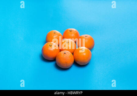 Sonnensymbol aus sechs bunte frische Orangen Mandarinen angelegt auf blaue Tabelle oben gesehen mit Textfreiraum Stockfoto