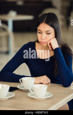 Mädchen sitzt in einem Café, Requisiten seine Hand auf die Wange. Müde, ruhigen Ausdruck. Stockfoto