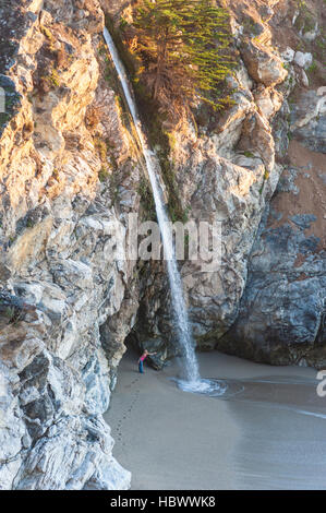 Blick von oberhalb einer Frau am Strand versuchen klebfrei McWay Falls auf Julia Pfeiffer Burns State Park, Kalifornien, USA. Stockfoto