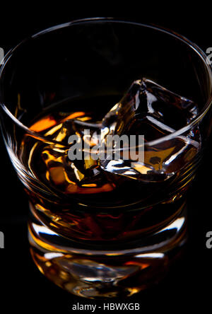 Glas Whiskey mit goldenen Eiswürfel auf schwarzem Hintergrund isoliert Stockfoto