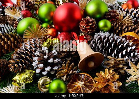 Weihnachten Hintergrund mit roten Verzierungen und verschneiten Tannenzapfen. Weihnachts-Dekoration mit hölzernen Glöckchen und Glaskugeln. Stockfoto