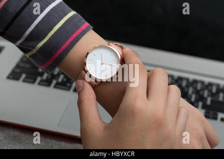 Mädchens Hand mit Armbanduhr vor Notebook-computer Stockfoto