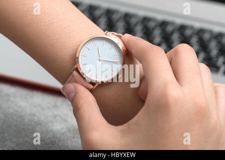 Mädchens Hand mit Armbanduhr vor Schreibtisch mit Notebook Stockfoto