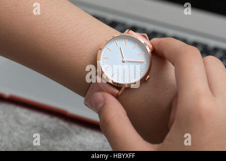 Mädchens Hand mit Armbanduhr vor Schreibtisch mit Notebook Stockfoto