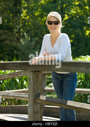 Blonde Frau auf einer hölzernen Brücke Stockfoto
