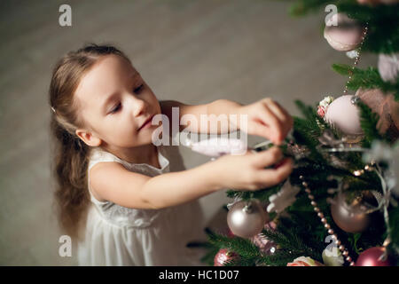 Niedliche kleine Mädchen im Kleid schmücken Weihnachtsbaum Stockfoto