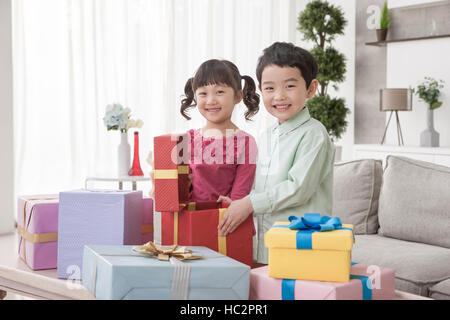 Lächelnden jungen und Mädchen, die Eröffnung eines viel Geschenkkartons im Wohnzimmer Stockfoto