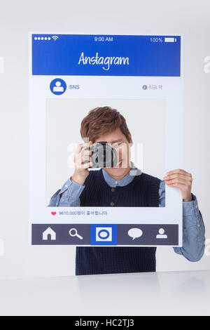 Porträt des jungen lächelnder Mann posiert mit Kamera auf SNS Stockfoto