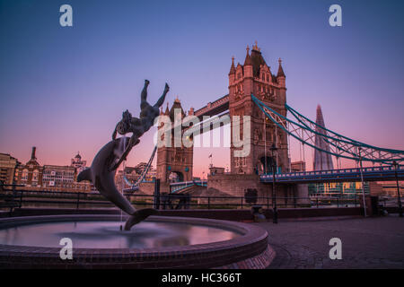 Tower Bridge mit der Meerjungfrau und Delphin-Statue in der Morgendämmerung. Stockfoto