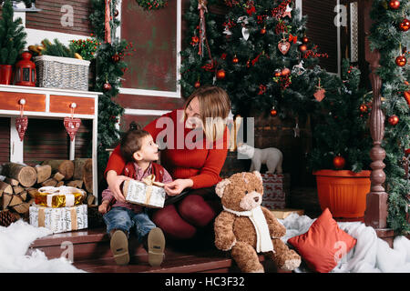 Schöne Frau gibt ein Geschenk an seinen Sohn. Junge und Frau anlächeln einander. Stockfoto