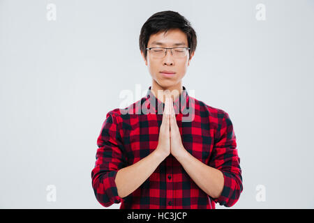 Bild von ernster junger Mann in lässigen Shirt in einem Käfig gekleidet und tragen Brillen betenden Geste und isoliert auf weißem Hintergrund Stockfoto