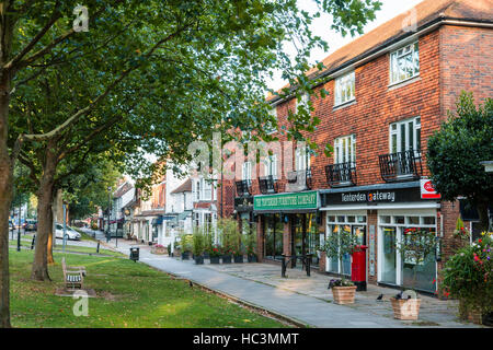 England, Tenterden. Die Grüns. Von Bäumen gesäumten Straßen mit modernen Gebäude mit Geschäften und der Post. Hintergrund, älteren viktorianischen Reihe kleiner Geschäfte. Stockfoto